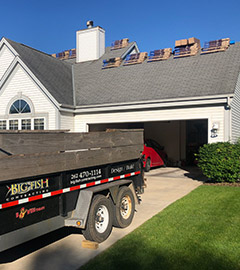 Photo of trailer with Big Fish logo on it parked in front of house with roofing materials
